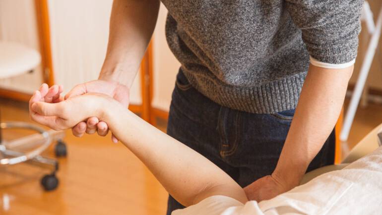 crop chiropractor massaging hand of patient