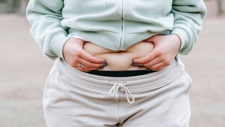 crop unrecognizable plump woman demonstrating fat on belly